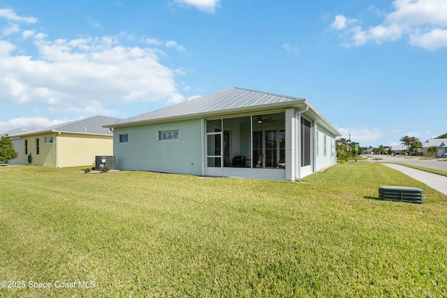 back of house featuring a lawn, a sunroom, and central air condition unit