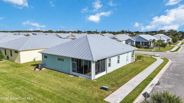 rear view of property featuring a sunroom, central AC unit, and a lawn