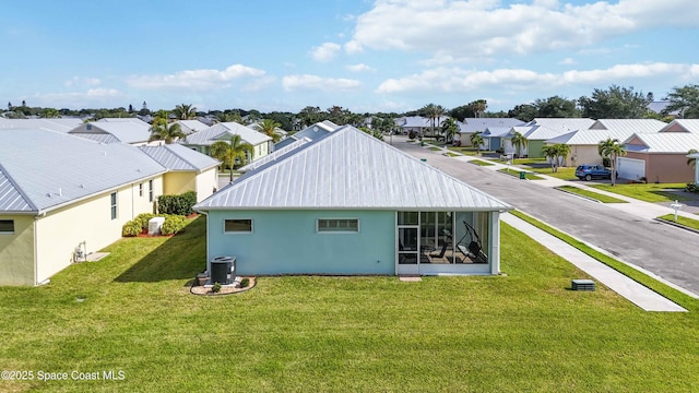 back of property with a sunroom, central AC unit, and a yard