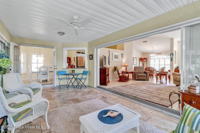 living room with ceiling fan with notable chandelier and a wealth of natural light