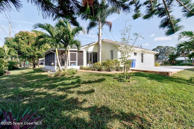 rear view of house featuring a sunroom and a yard