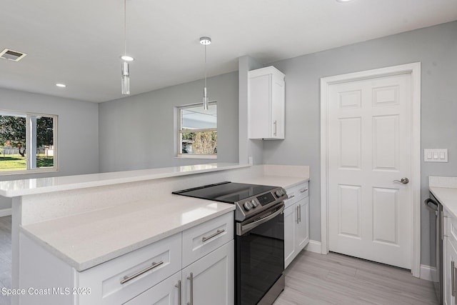 kitchen with electric stove, kitchen peninsula, white cabinets, and hanging light fixtures