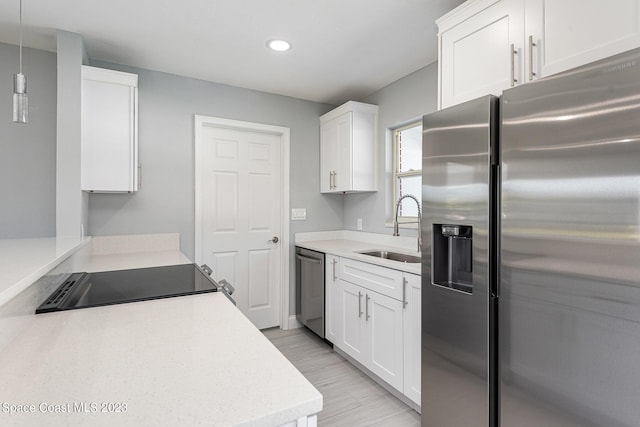 kitchen with appliances with stainless steel finishes, white cabinetry, pendant lighting, and sink