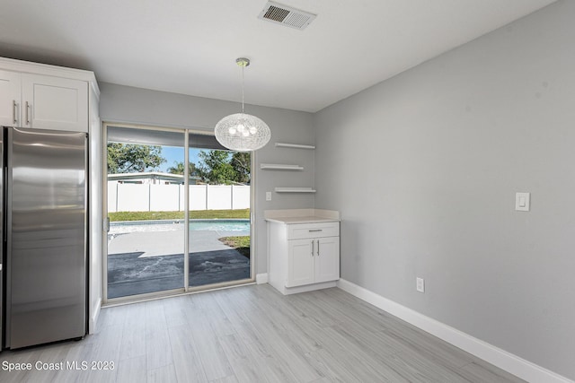 unfurnished dining area featuring a notable chandelier and light wood-type flooring