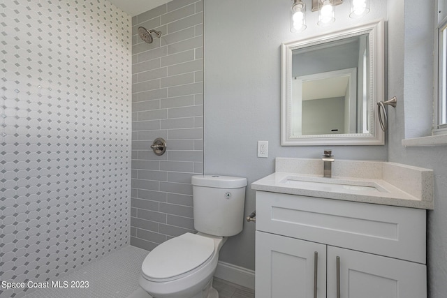 bathroom with tiled shower, vanity, and toilet