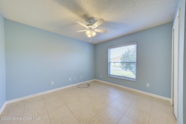 empty room with ceiling fan, light tile patterned flooring, and a textured ceiling