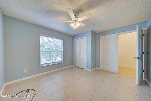 unfurnished bedroom featuring light tile patterned floors, a textured ceiling, a closet, and ceiling fan