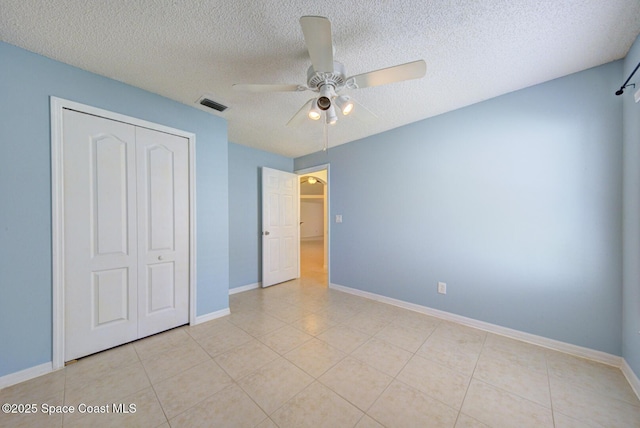 unfurnished bedroom with light tile patterned floors, a textured ceiling, a closet, and ceiling fan