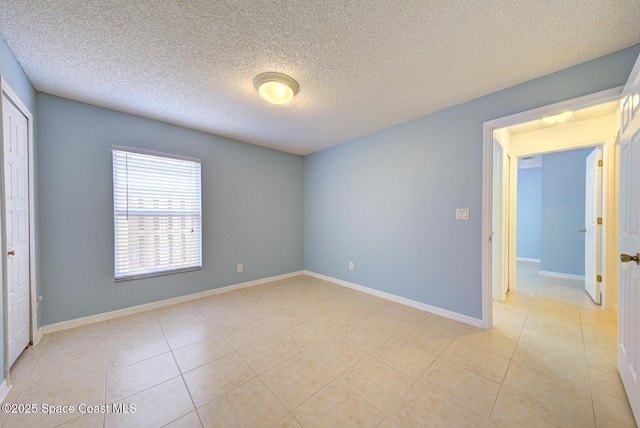 spare room with light tile patterned floors and a textured ceiling