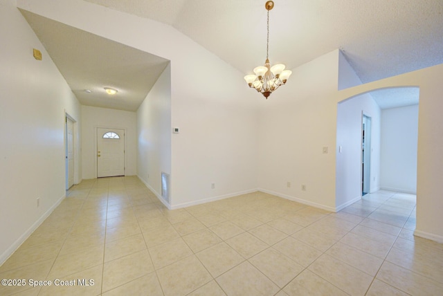 tiled empty room with a chandelier, a textured ceiling, and vaulted ceiling