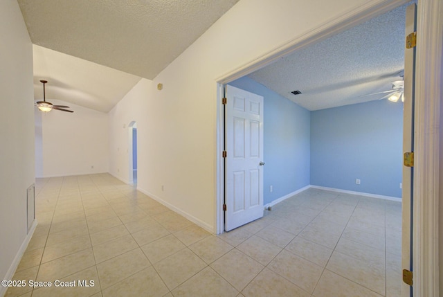 hallway featuring light tile patterned floors, a textured ceiling, and vaulted ceiling