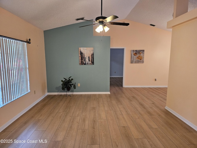 spare room with ceiling fan, a healthy amount of sunlight, lofted ceiling, and light wood-type flooring