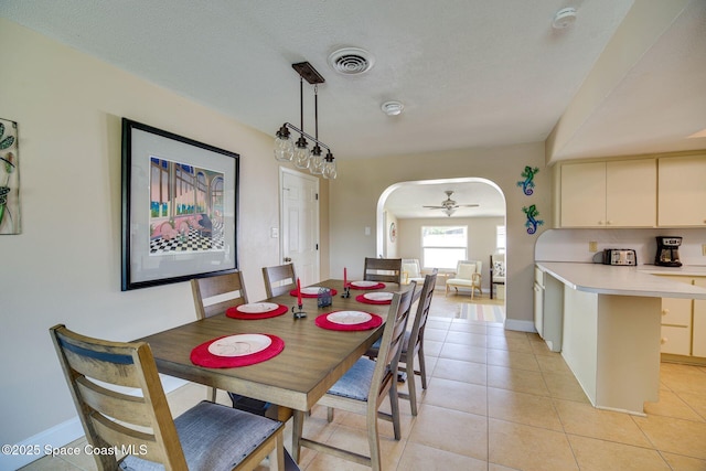 tiled dining room with ceiling fan and a textured ceiling