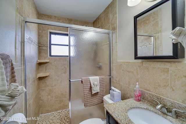 bathroom with vanity, toilet, an enclosed shower, and tile walls