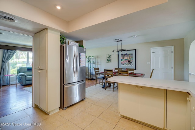 kitchen featuring stainless steel refrigerator, light tile patterned flooring, and pendant lighting