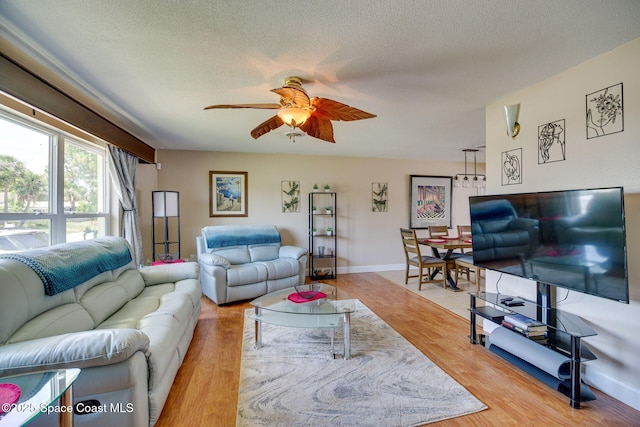 living room featuring hardwood / wood-style floors, ceiling fan, and a textured ceiling