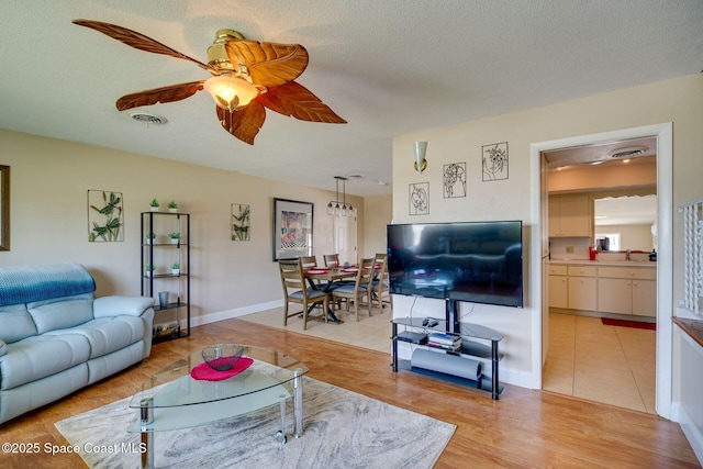 tiled living room with ceiling fan, sink, and a textured ceiling