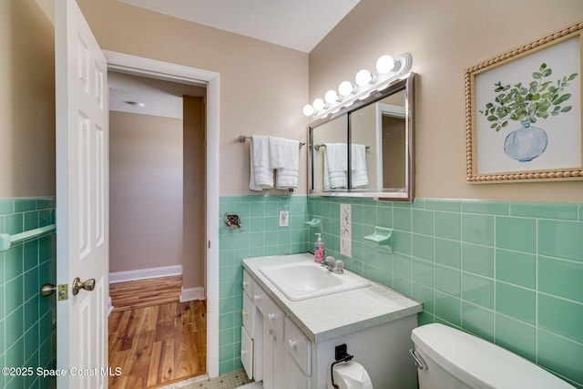 bathroom with hardwood / wood-style floors, vanity, toilet, and tile walls