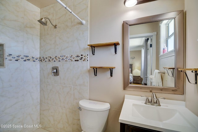 bathroom with a tile shower, vanity, and toilet