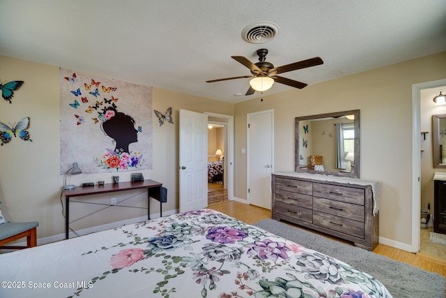 bedroom with connected bathroom, ceiling fan, light hardwood / wood-style flooring, and a textured ceiling