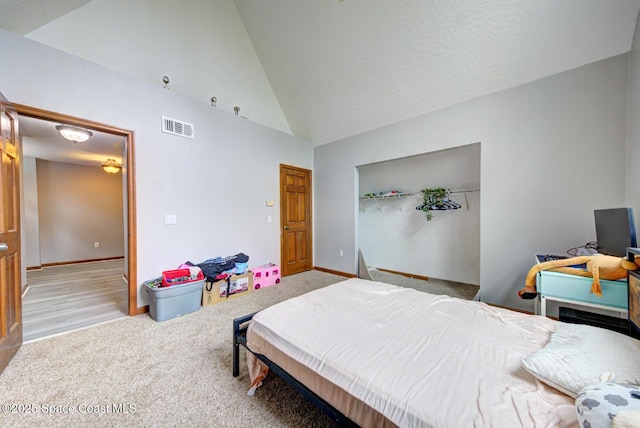 bedroom with light colored carpet, high vaulted ceiling, and a closet