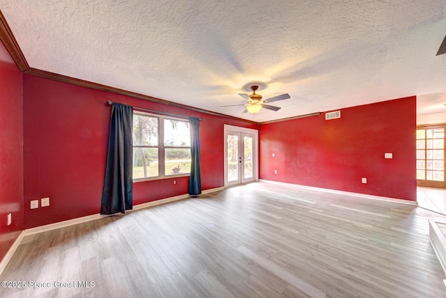 unfurnished room featuring french doors, crown molding, ceiling fan, light wood-type flooring, and a textured ceiling