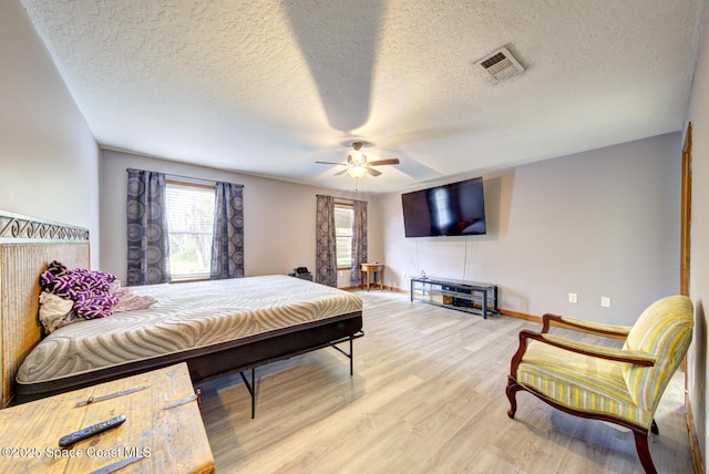 bedroom with ceiling fan, a textured ceiling, and light wood-type flooring