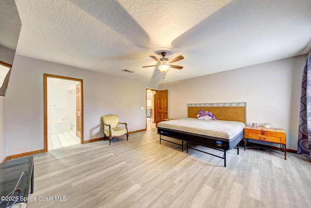 bedroom featuring ceiling fan, light wood-type flooring, a textured ceiling, and ensuite bath