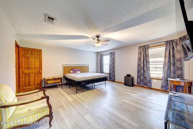 bedroom with a textured ceiling, light hardwood / wood-style flooring, and ceiling fan