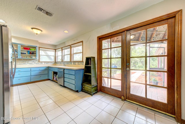 kitchen with sink, french doors, decorative backsplash, light tile patterned flooring, and appliances with stainless steel finishes