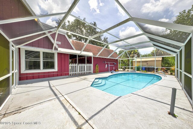 view of pool with glass enclosure, a patio, and an outdoor structure