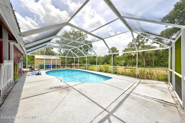 view of pool with glass enclosure, a shed, and a patio