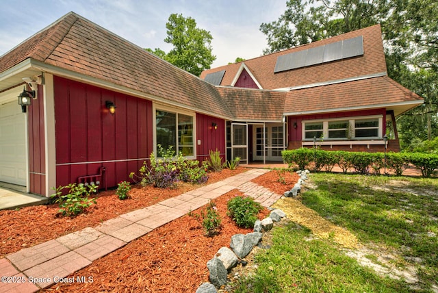 view of front of home with a front lawn, a garage, and solar panels