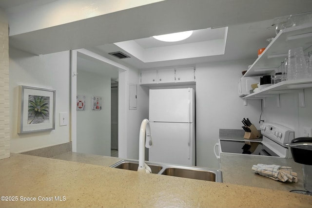 kitchen with a raised ceiling, sink, white cabinets, and white appliances