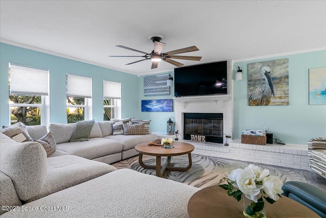 living room featuring a brick fireplace, ornamental molding, and ceiling fan