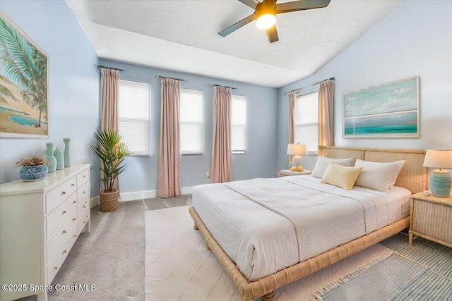 bedroom with ceiling fan, light colored carpet, vaulted ceiling, and multiple windows