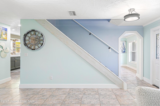 staircase with crown molding, tile patterned floors, and a textured ceiling