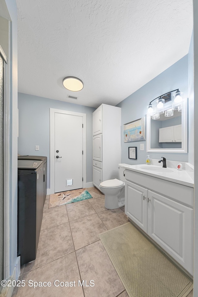 bathroom featuring vanity, a textured ceiling, tile patterned floors, and toilet