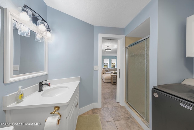 bathroom with washer / clothes dryer, vanity, tile patterned flooring, and an enclosed shower