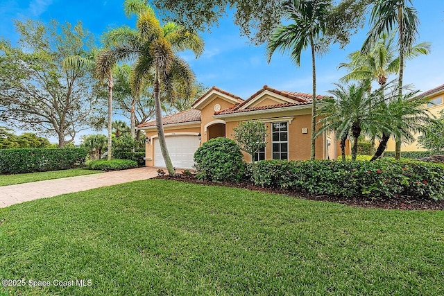 mediterranean / spanish house featuring a front lawn, a tiled roof, stucco siding, driveway, and an attached garage