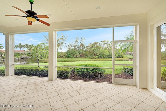 unfurnished sunroom with ceiling fan and a water view