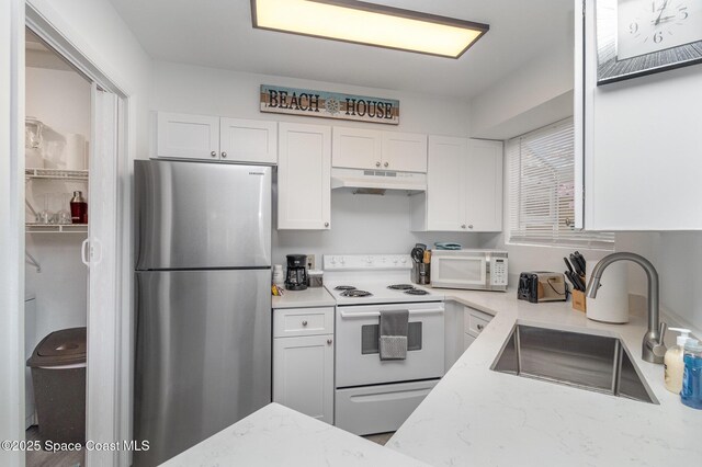 kitchen with white cabinets, light stone counters, white appliances, and sink