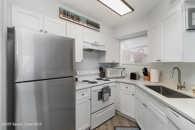 kitchen with light stone countertops, white appliances, sink, light hardwood / wood-style flooring, and white cabinetry