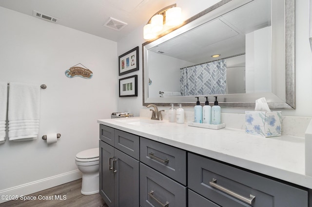 bathroom with hardwood / wood-style floors, vanity, toilet, and walk in shower