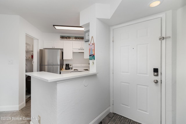 kitchen with hardwood / wood-style floors, white cabinetry, kitchen peninsula, and stainless steel refrigerator