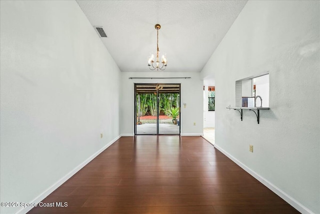 interior space with dark wood-type flooring, a chandelier, and a textured ceiling