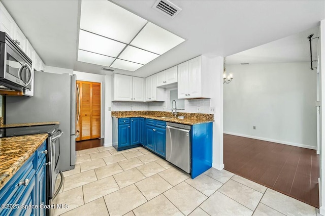 kitchen featuring blue cabinetry, appliances with stainless steel finishes, a notable chandelier, light tile patterned flooring, and white cabinetry