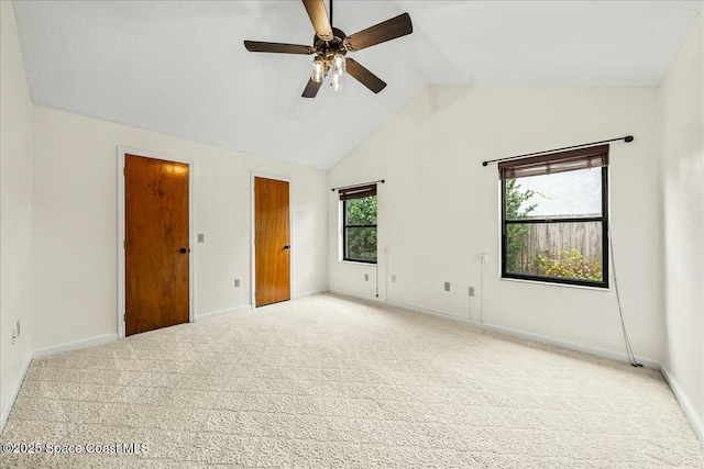 carpeted spare room featuring a wealth of natural light, ceiling fan, and lofted ceiling