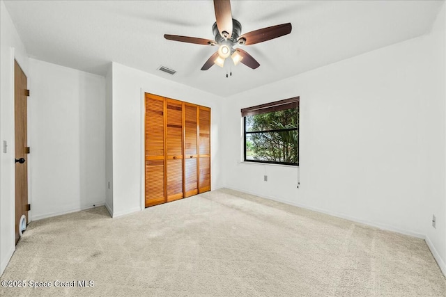 unfurnished bedroom with light carpet, a closet, and ceiling fan