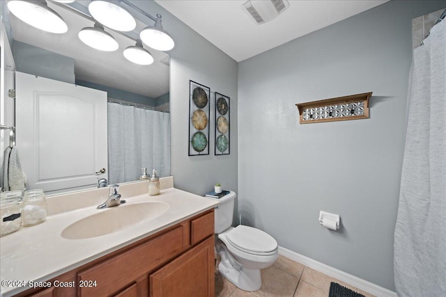 bathroom with toilet, vanity, and tile patterned floors